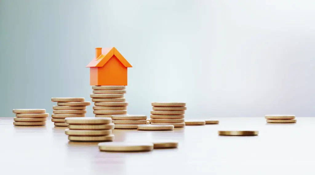 Small model house resting on stacks of coins, representing the interest paid over a mortgage term