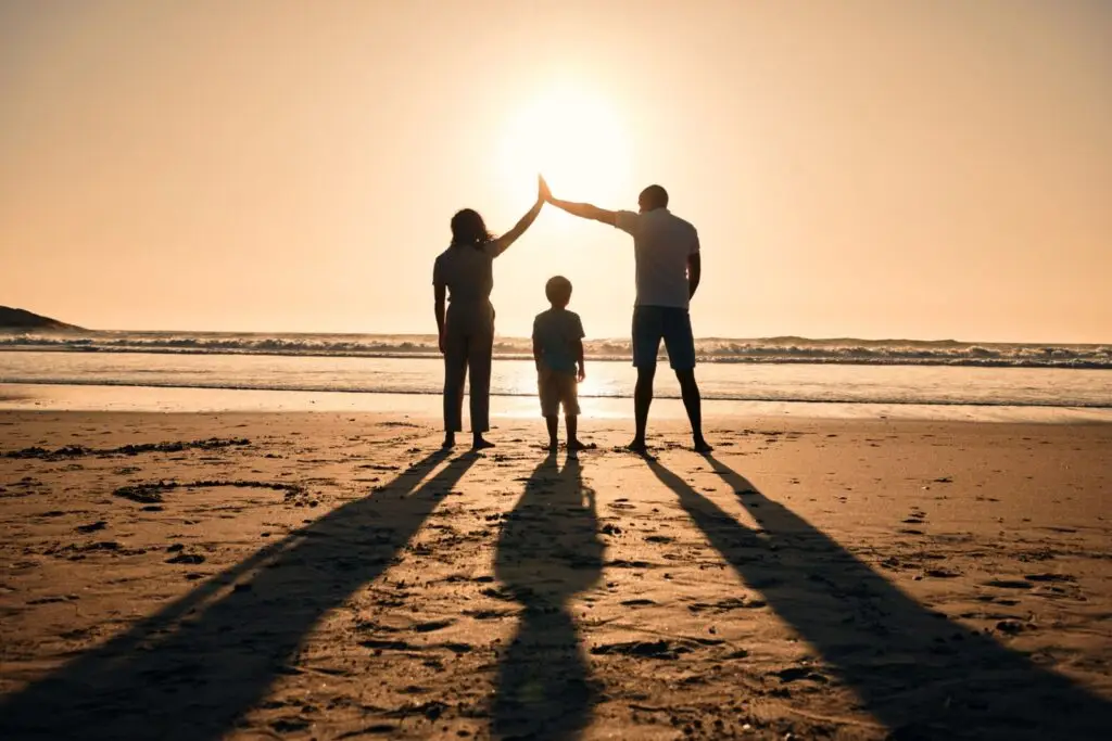 Family silhouetted on a beach at sunset, representing long term financial goals