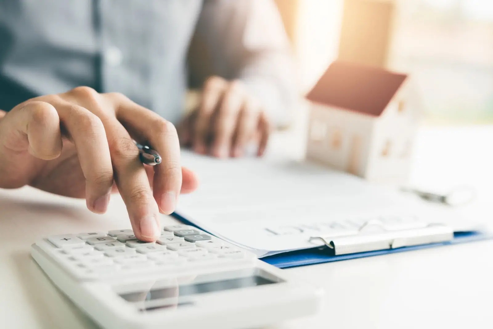 Homebuyer working out mortgage points with a calculator next to a small house model