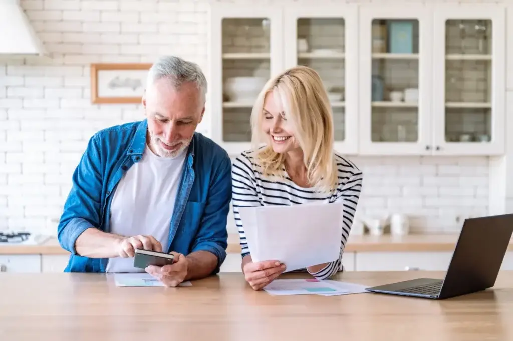 Retired couple reviewing retirement income statements and mortgage documents at their kitchen table