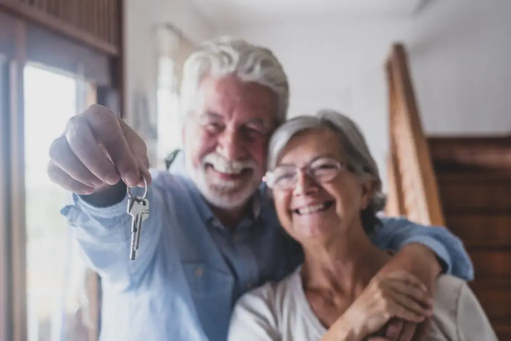Retired couple smiling and holding the keys to their new home